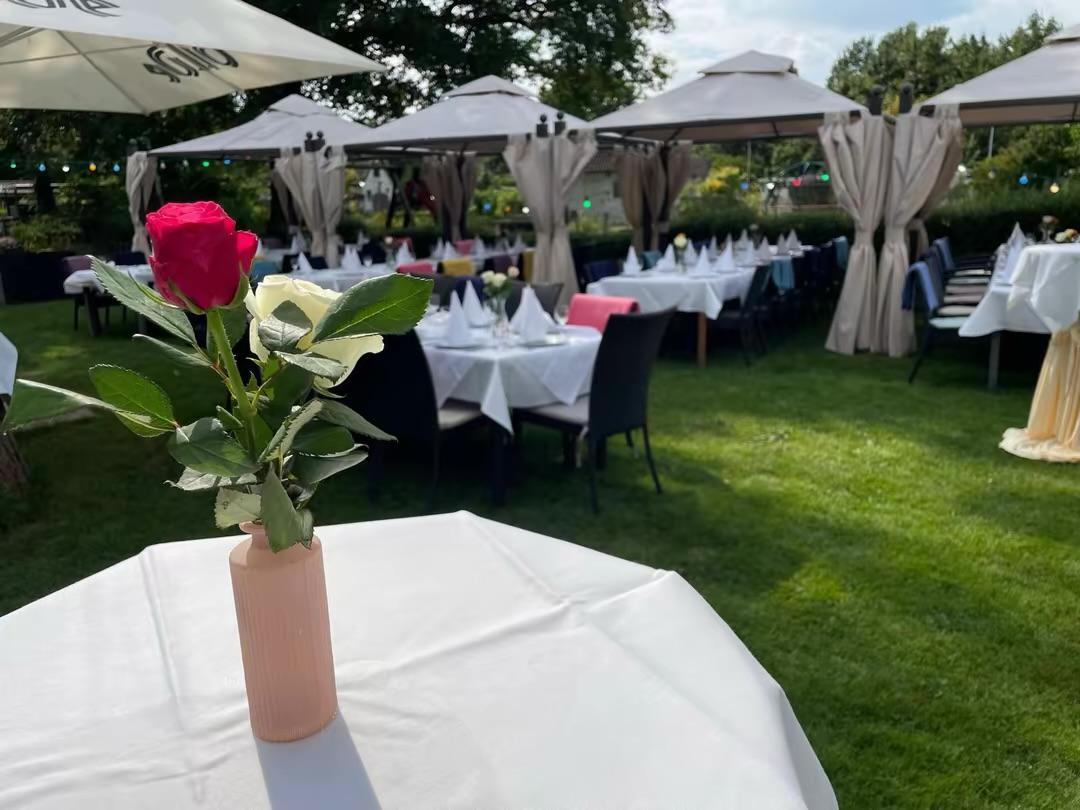 Rosen in einer Vase auf einem Tisch im Garten mit Pavillons im Hintergrund
