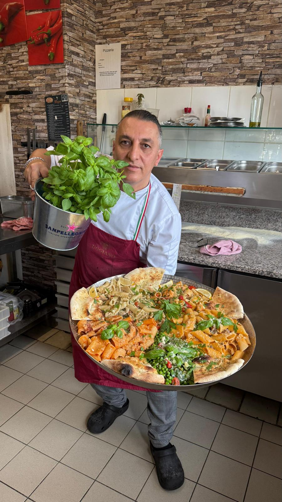 Küchenchef mit frischem Pasta-Platte aus der Steinofen-Küche