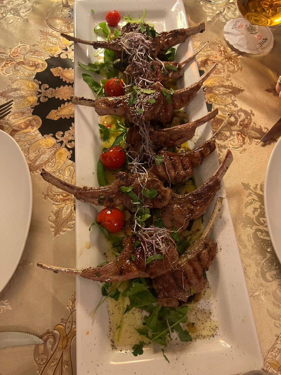 Gegrillte Lammkoteletts mit Rucola und Kirschtomaten auf einer Platte