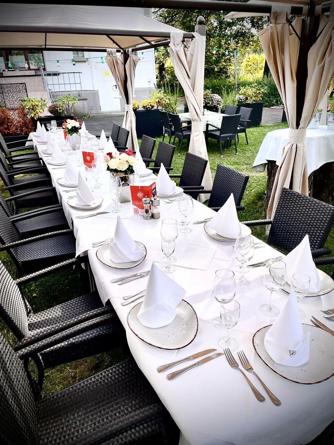 Festlich gedeckte lange Tafel im Gartenpavillon